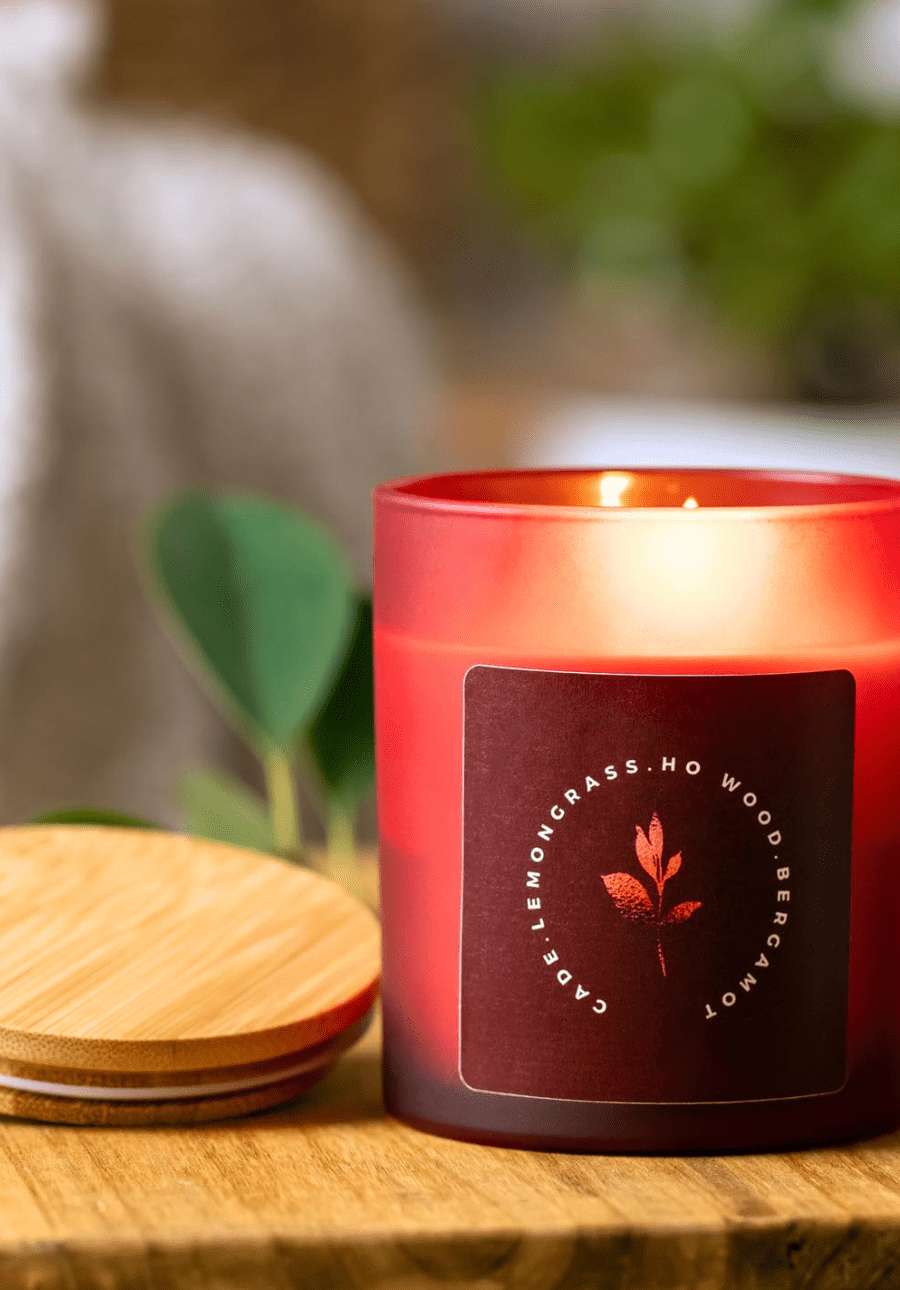 Red candle with a label on a wooden surface